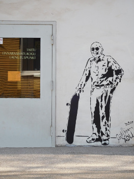 the door of the lubja service point and an old man with a skateboard graffitied on the wall next to it