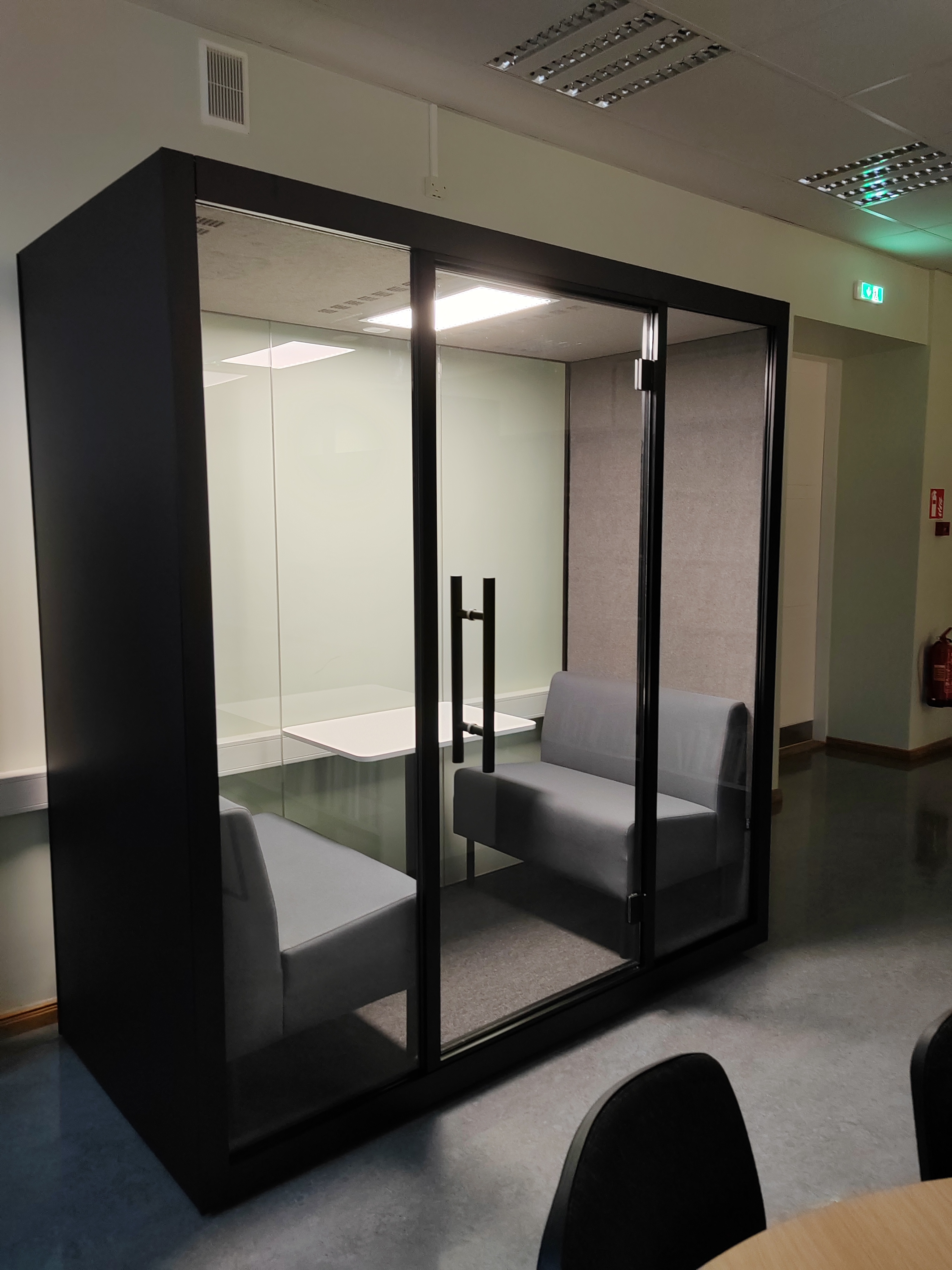 Vaikusekabiin foto: klaasist ustega helikindel kabiin, milles on laud ja kaks kahekohalist diivanit